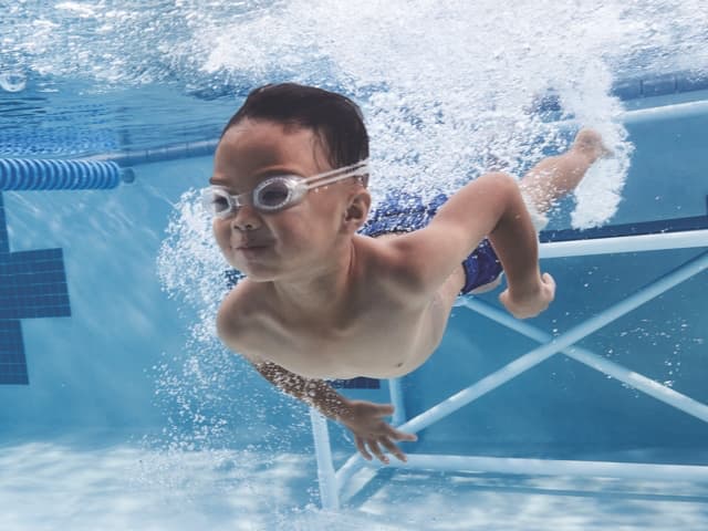 Young boy swimming underwater with goggles on