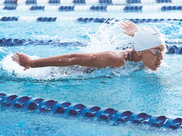 Image of a female swimming butterfly down a pool lane